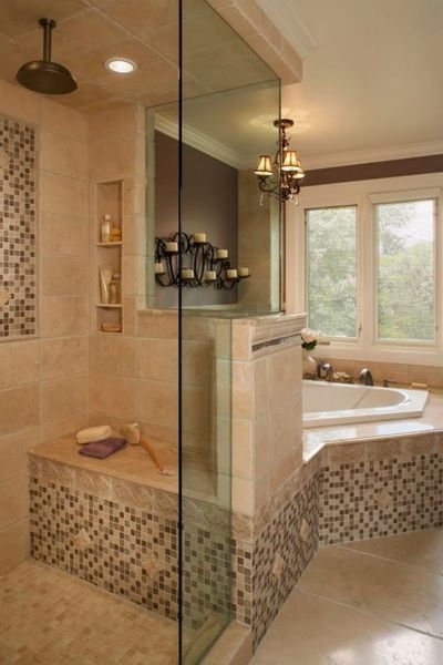 Beige-tiled bathroom with glass shower, built-in bench, and mosaic accent. A tub with window view and a candle display is on the right.