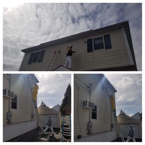 Person painting the trim of a two-story house, using a ladder. Cloudy sky.