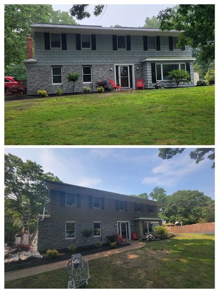 Two-story house with gray siding and black shutters; green lawn; sunny day.