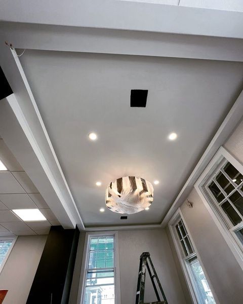 Low-angle view of a room's ceiling with a recessed light fixture and a patterned light fixture.