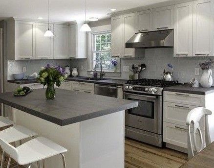 White kitchen with island, gray countertops, stainless steel appliances, and white cabinets.