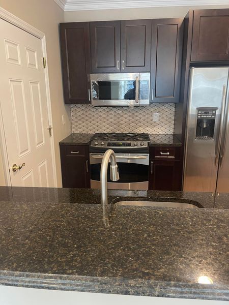 Kitchen with dark brown cabinets, stainless steel appliances, and granite countertop.