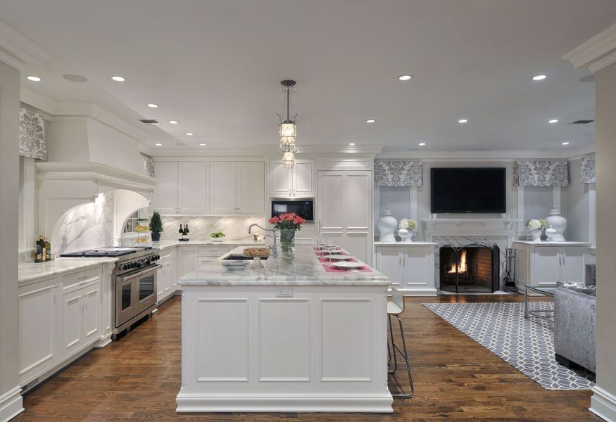White kitchen with island, fireplace, and wood floors.