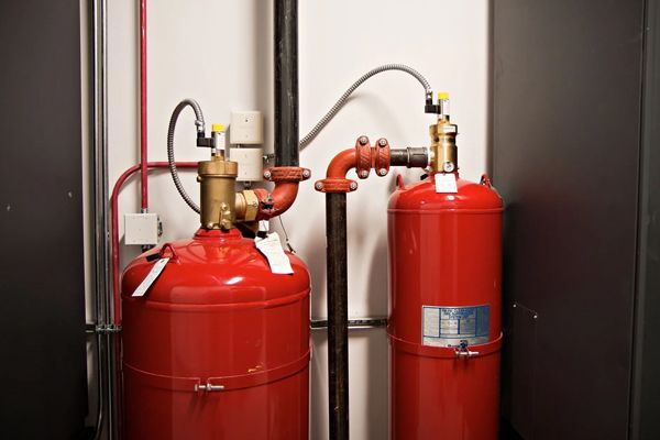 Two red fire extinguishers are sitting next to each other in a room.