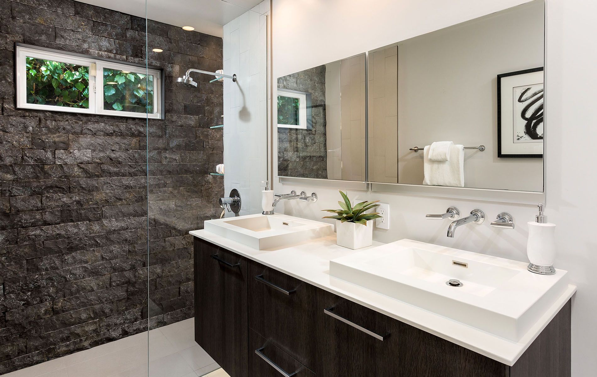 A bathroom with two sinks and a walk in shower.