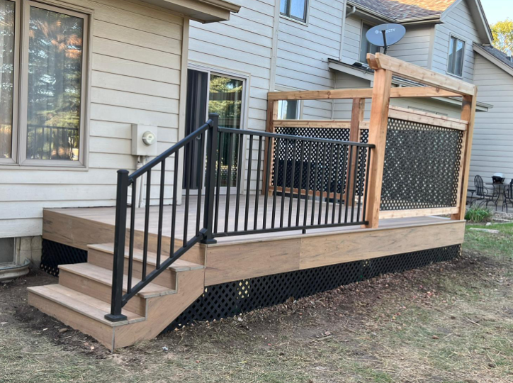 Wooden deck with black railing and lattice panels, attached to a house with steps.