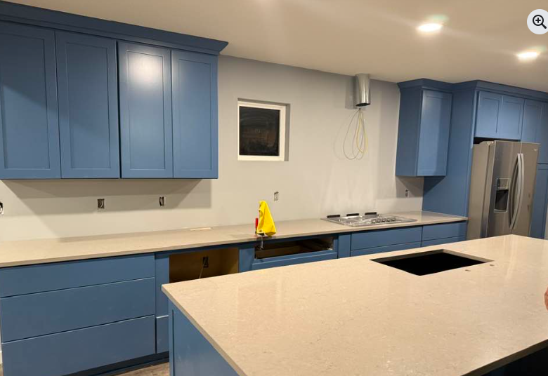 Blue kitchen cabinets with light countertops and an island; unfinished.