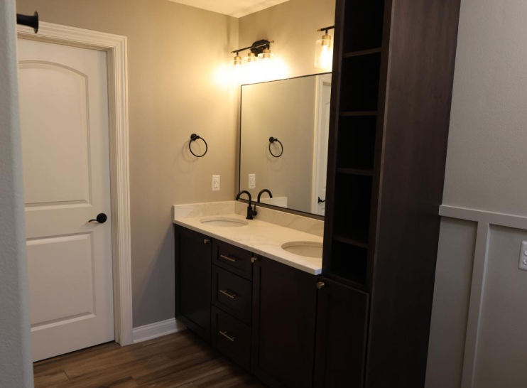 Bathroom with dark brown vanity, double sinks, and a built-in storage cabinet.