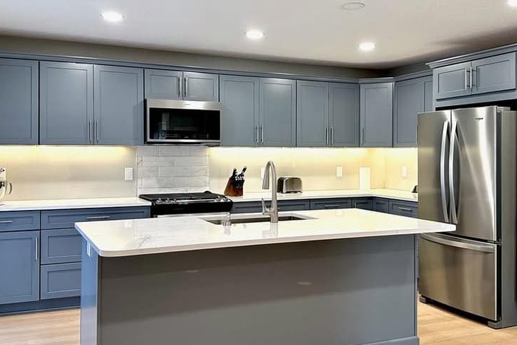 Modern blue kitchen with white countertops, stainless steel appliances, and island.