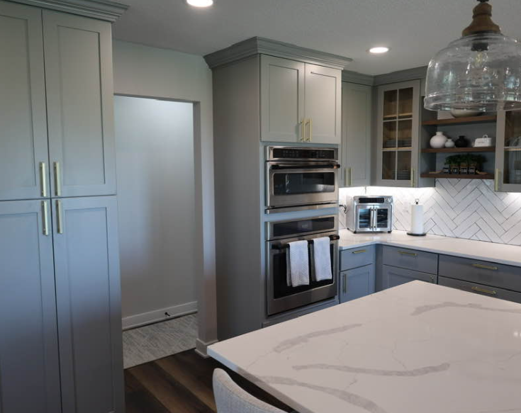 Gray kitchen with stainless steel appliances, a white countertop, and light-colored cabinets.