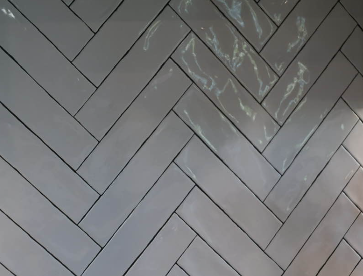 Herringbone pattern of pale gray rectangular tiles with dark grout lines.