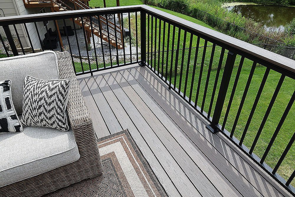 Wooden deck overlooking a scenic valley with a brown railing and a partly visible building.
