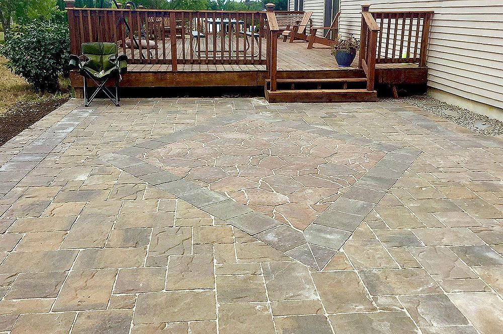Brick patio with star pattern next to a wooden deck.