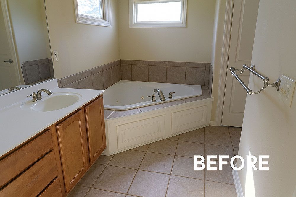 Bathroom before renovation with a tub, sink, and beige tile.