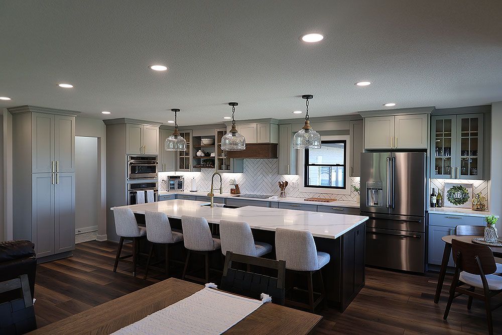 Spacious modern kitchen with island, gray cabinets, stainless steel appliances, and wood floor.