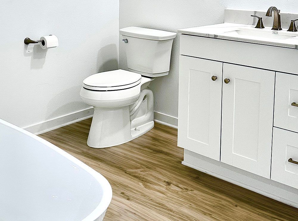 White bathroom with toilet, vanity, and a portion of a bathtub.