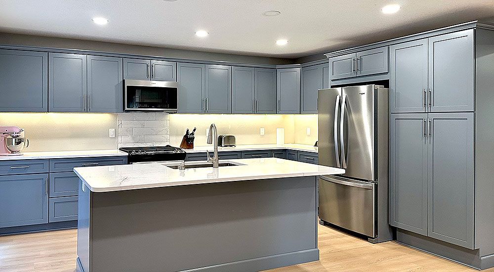 Gray kitchen with white countertops, stainless steel appliances, and island.
