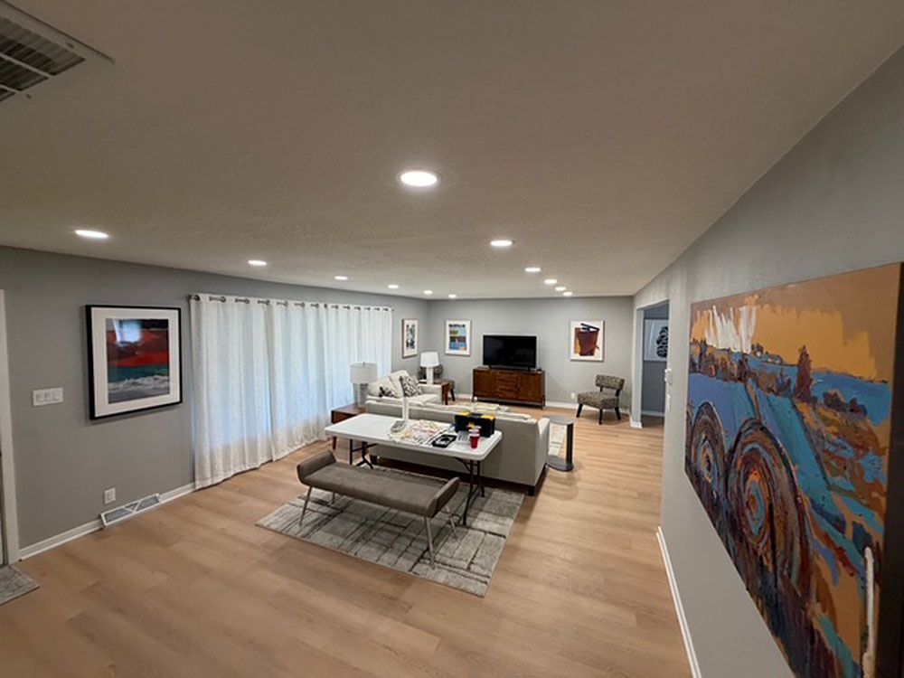 Living room with light wood floors, gray walls, modern furniture, and abstract art.