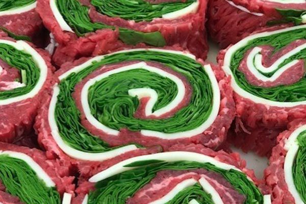 a close up of a swirl of meat and spinach on a plate .