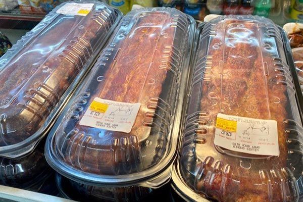 three pieces of meat are sitting on a shelf in plastic containers .