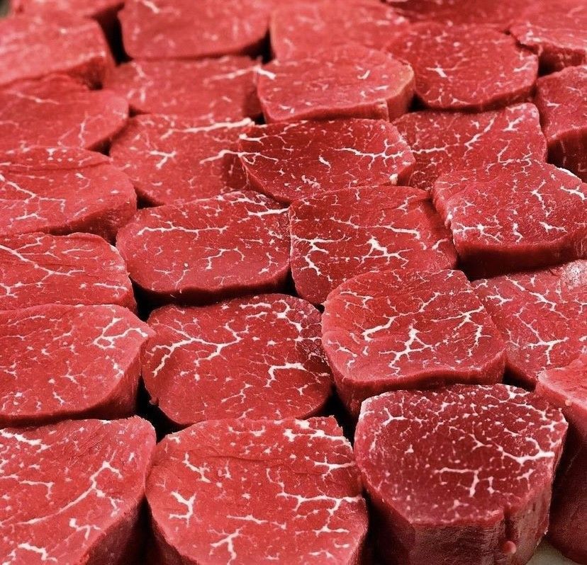 a bunch of steaks are stacked on top of each other