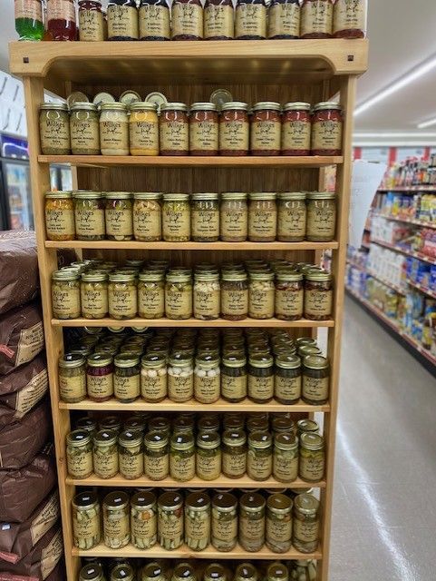 a wooden shelf filled with jars of food in a grocery store .
