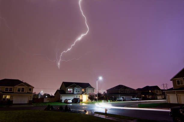 Lightning strikes over suburban houses at night.