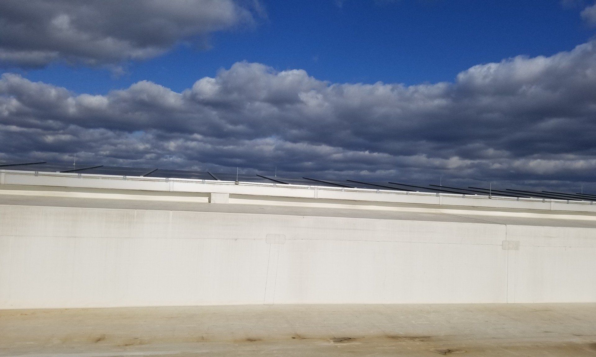 White building under a blue sky with cloudy formations on the roof.