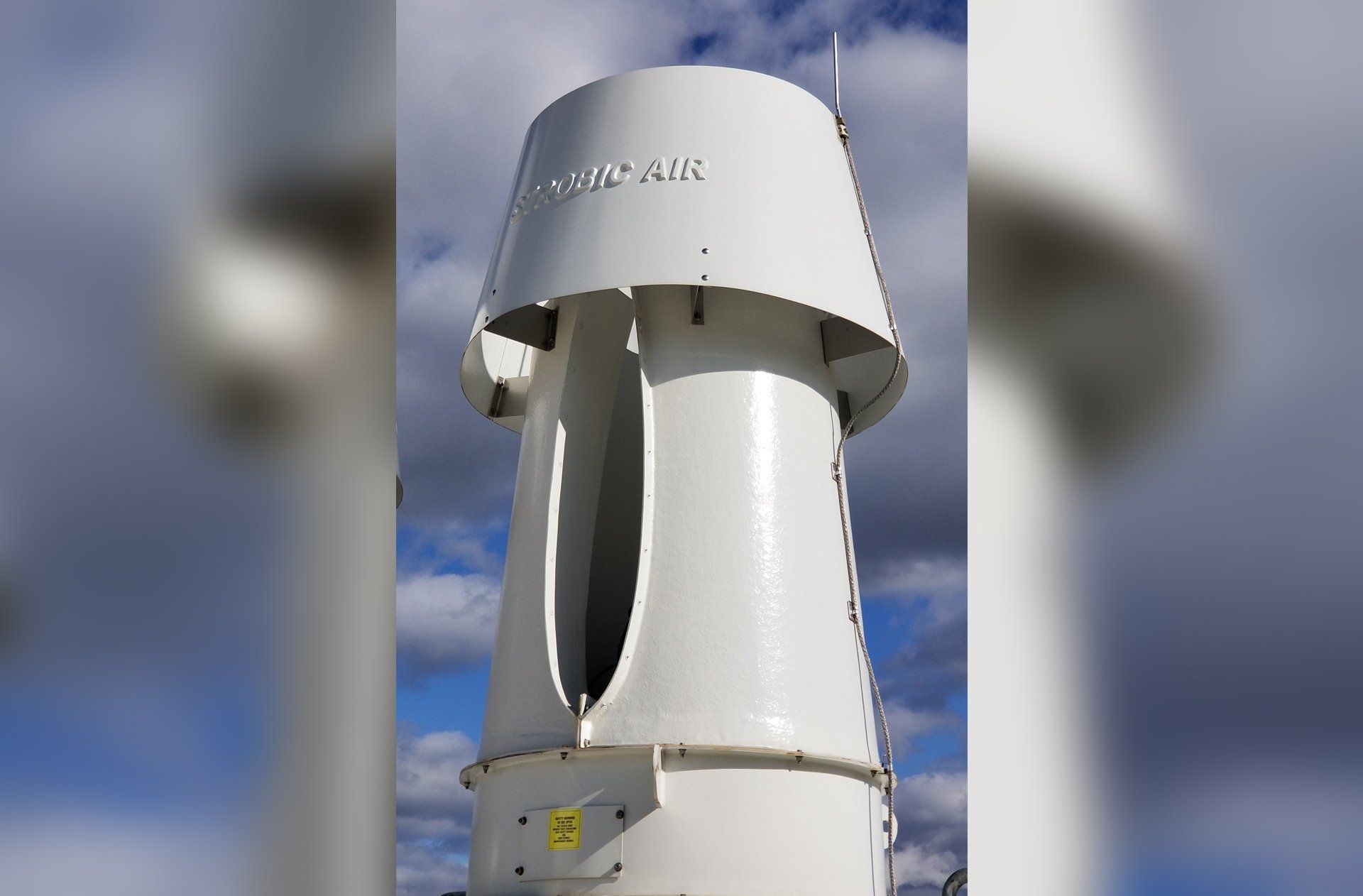 White cylindrical vent with angled top, exterior view, text 