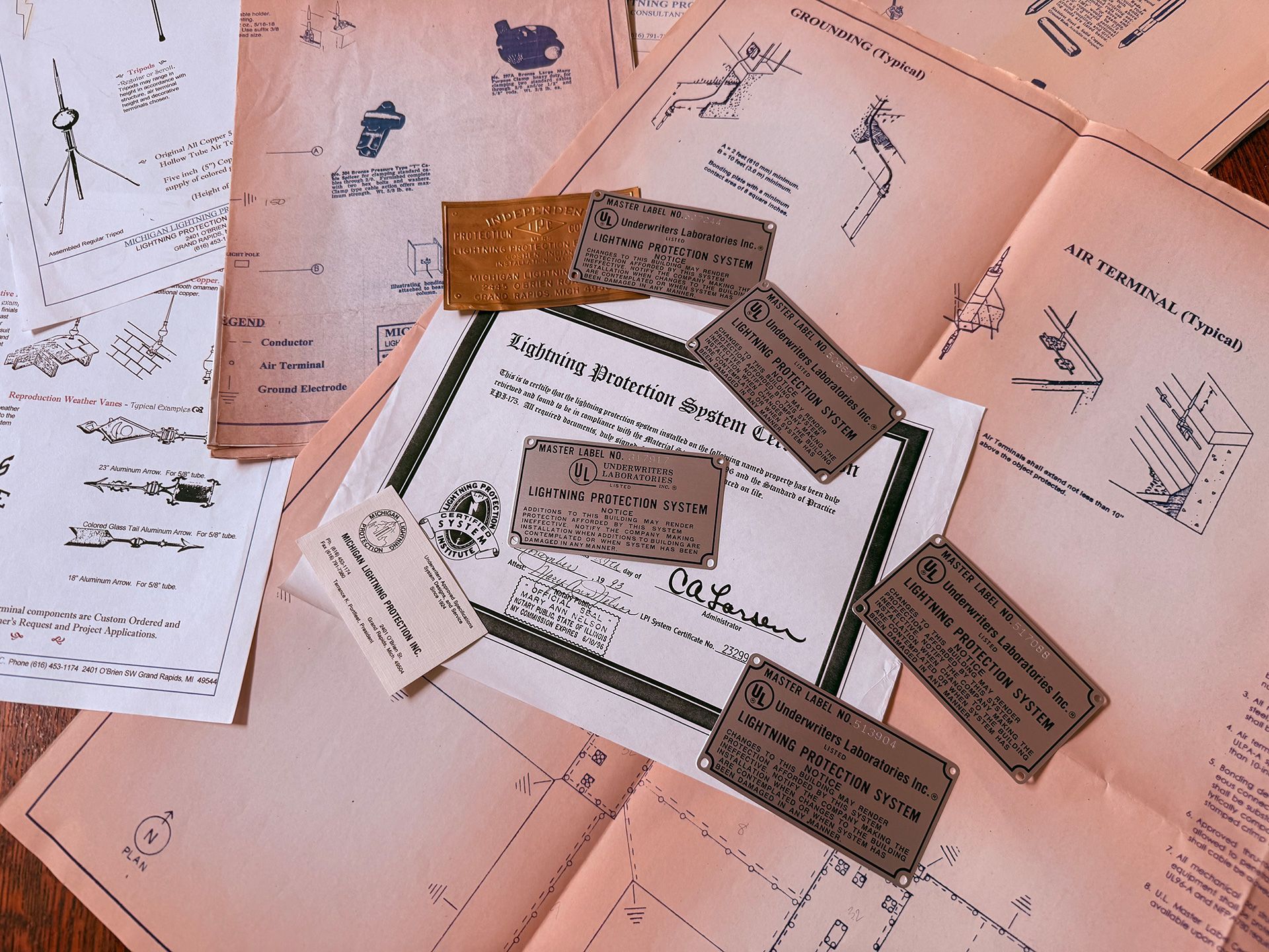 A collection of vintage-style blueprints, documents, and small metal placards featuring technical sketches and text.