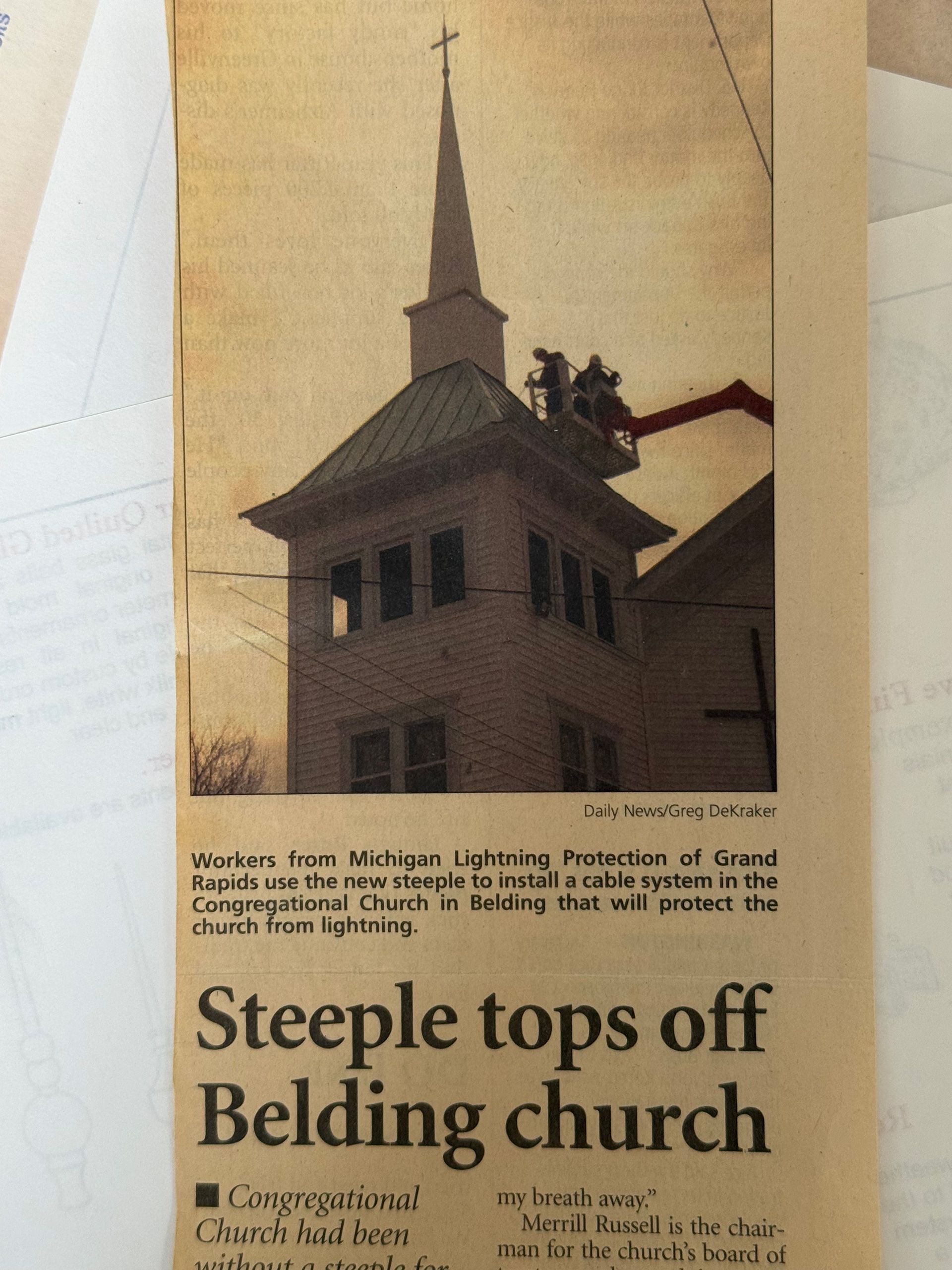 Workers in a cherry picker install a lightning protection system on the steeple of the Congregational Church in Belding.