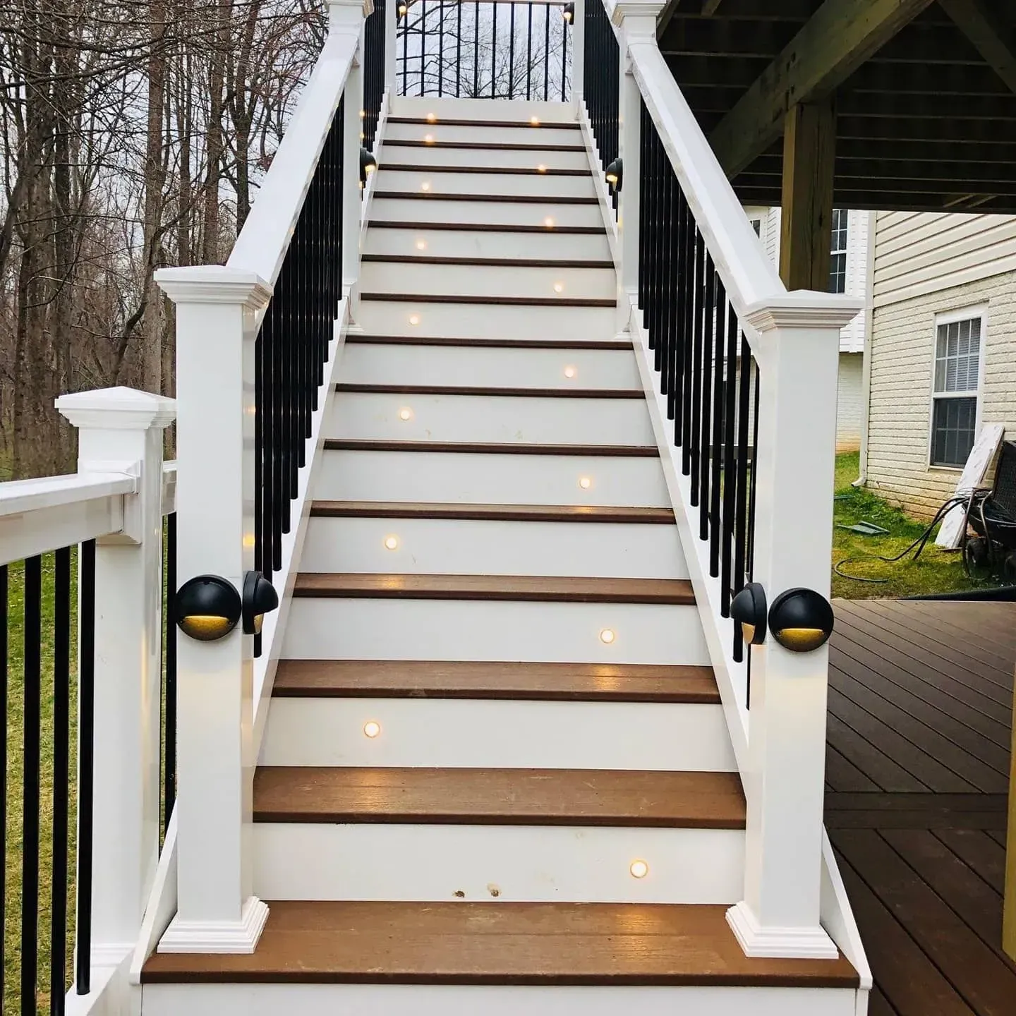 Staircase with white risers and brown treads, black railings, and embedded lights; exterior setting.