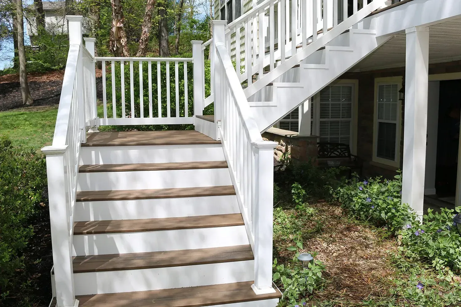 White outdoor staircase with wooden steps leading to a deck.