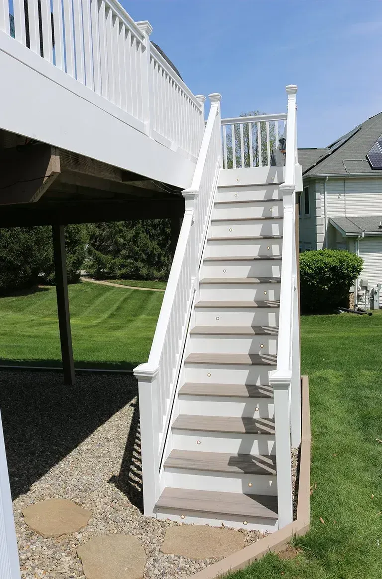 White deck stairs leading from a deck to a grassy yard.