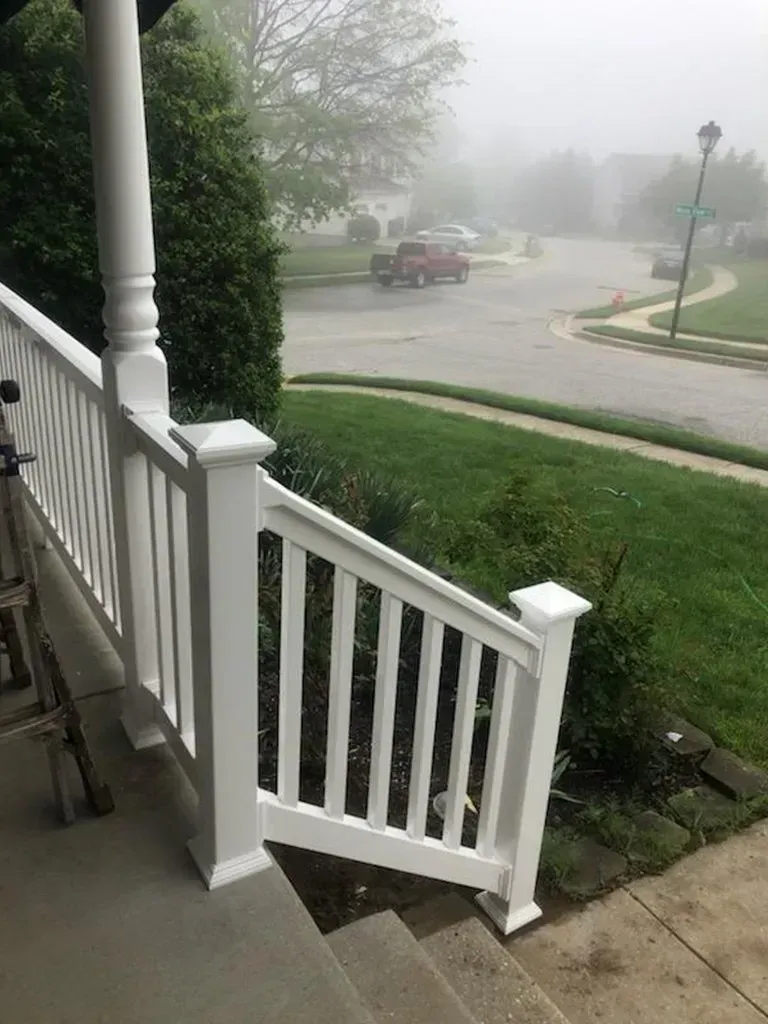 White porch railing on steps; a foggy street and houses are in the background.