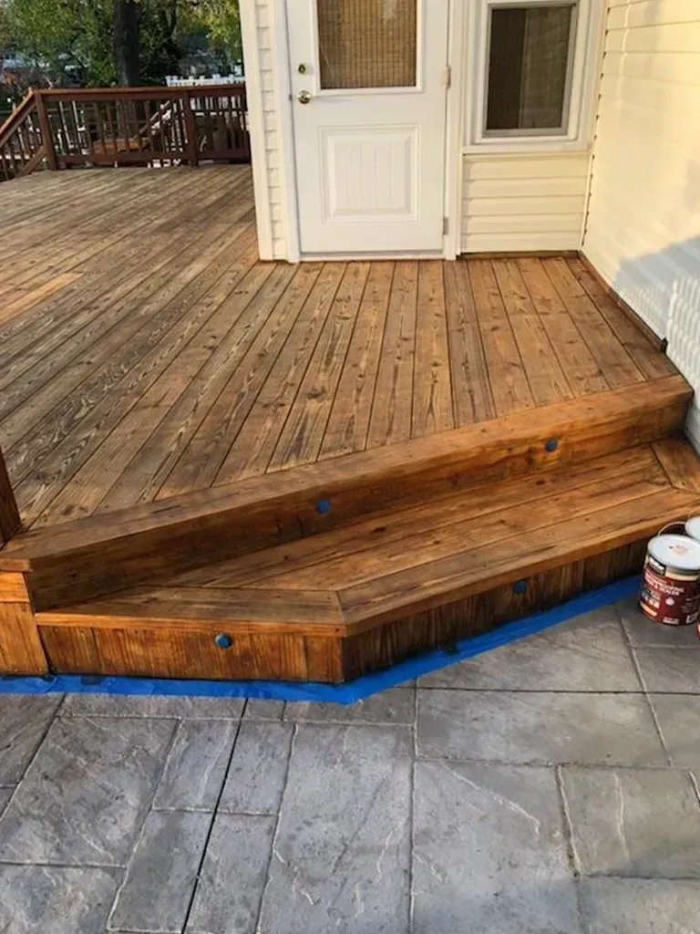 Wooden deck with steps leading to a white door. Blue tape lines edges.