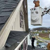 Person in lift working on roof. Building with dark roof, light siding.