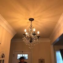 Chandelier hanging from a ceiling, person partially visible below.