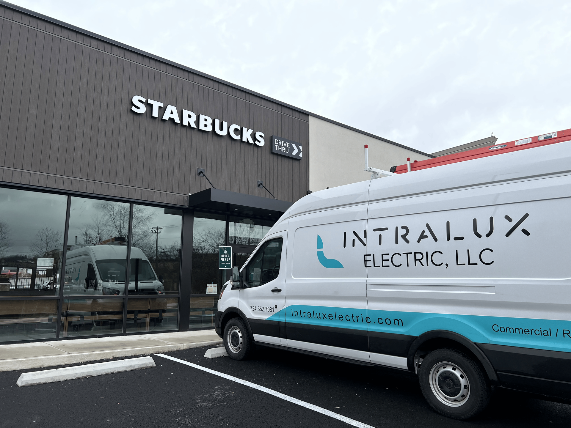 An Intralux Electric van parked outside a Starbucks.