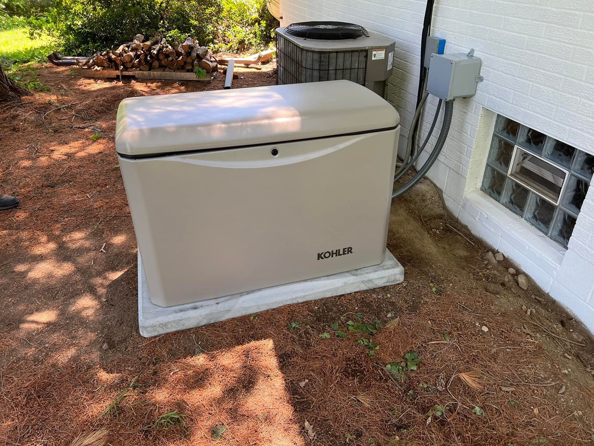 Tan generator on concrete pad next to a house with an air conditioner and window.