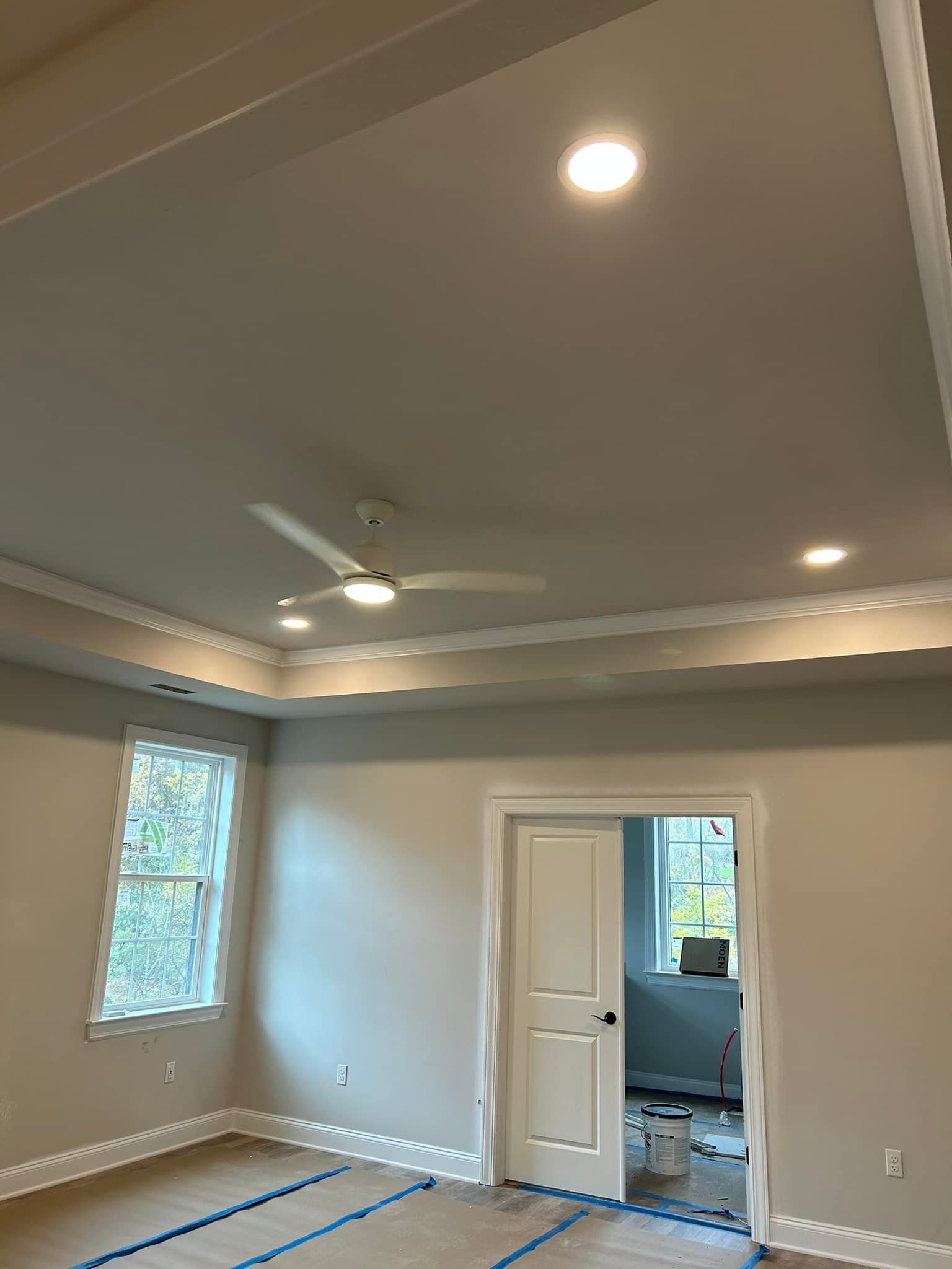 Ceiling with recessed lights, ceiling fan, crown molding, a window, and an open doorway.