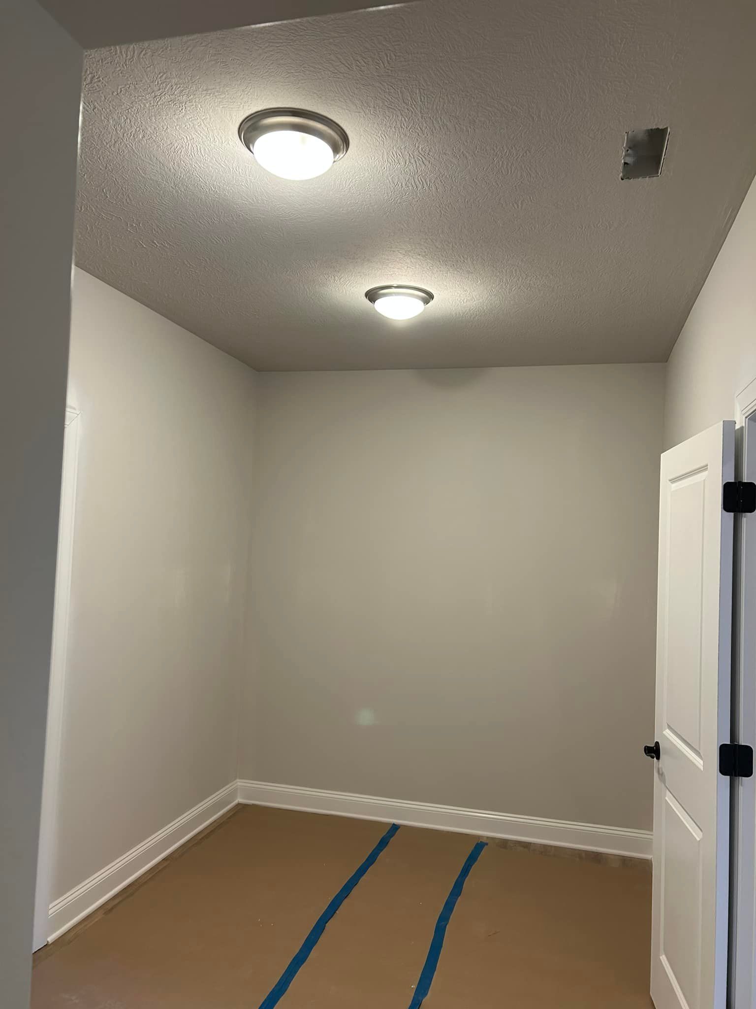 Small, empty room with two ceiling lights and a door on the right. 