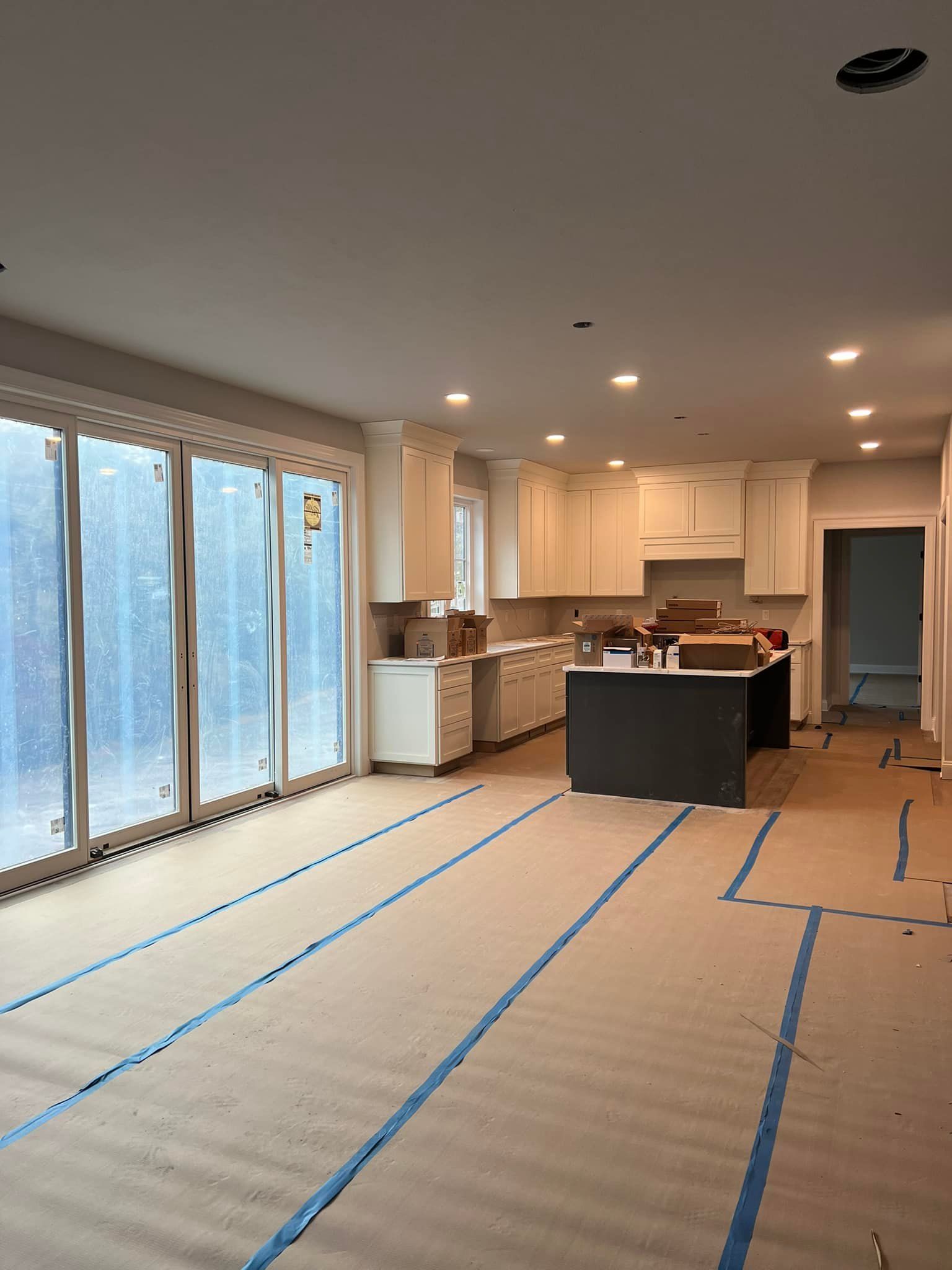 New kitchen under construction, with cabinetry, island, and large glass doors.
