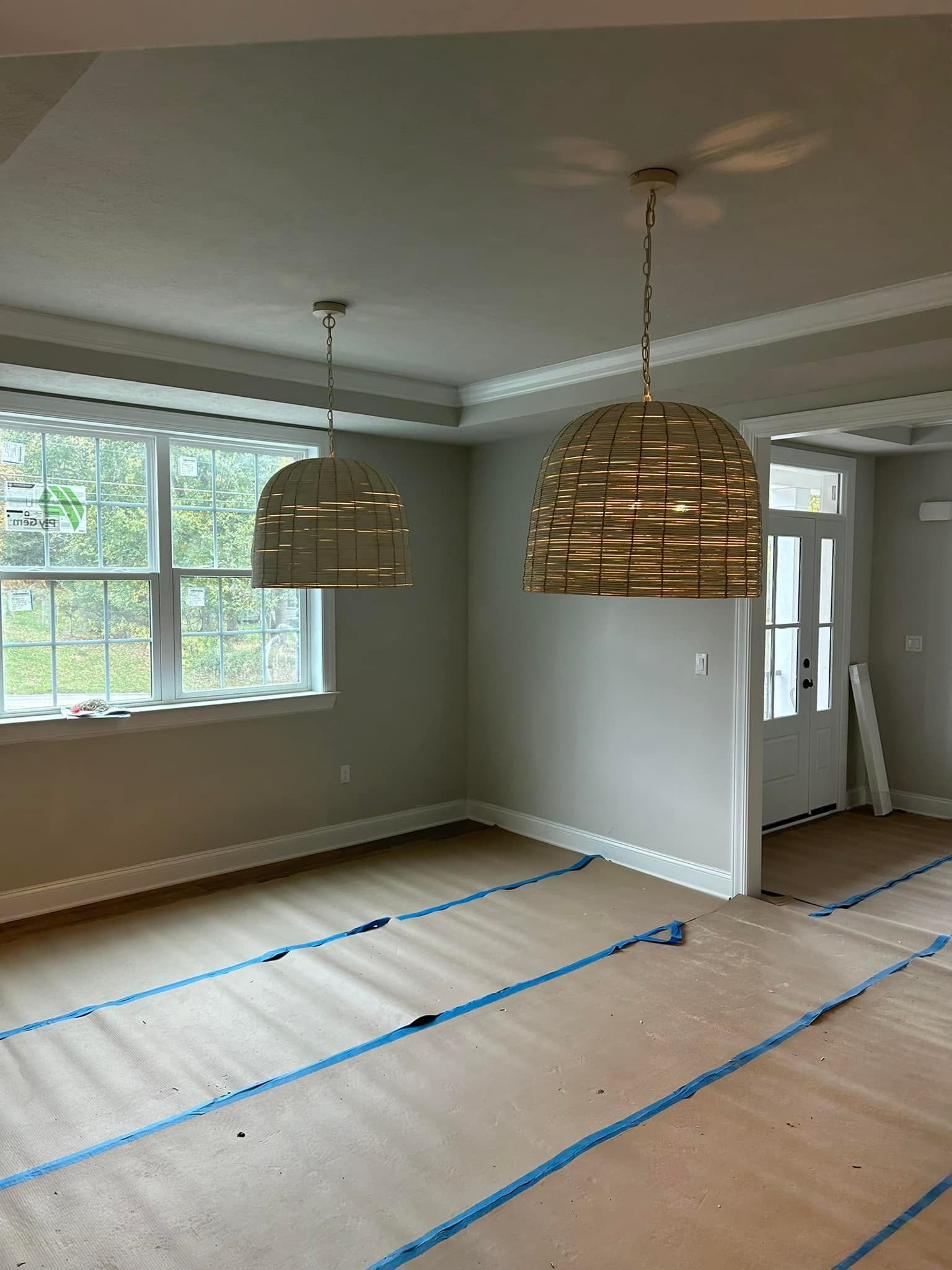 Two pendant lights in a new room with windows, door, and exposed floor.