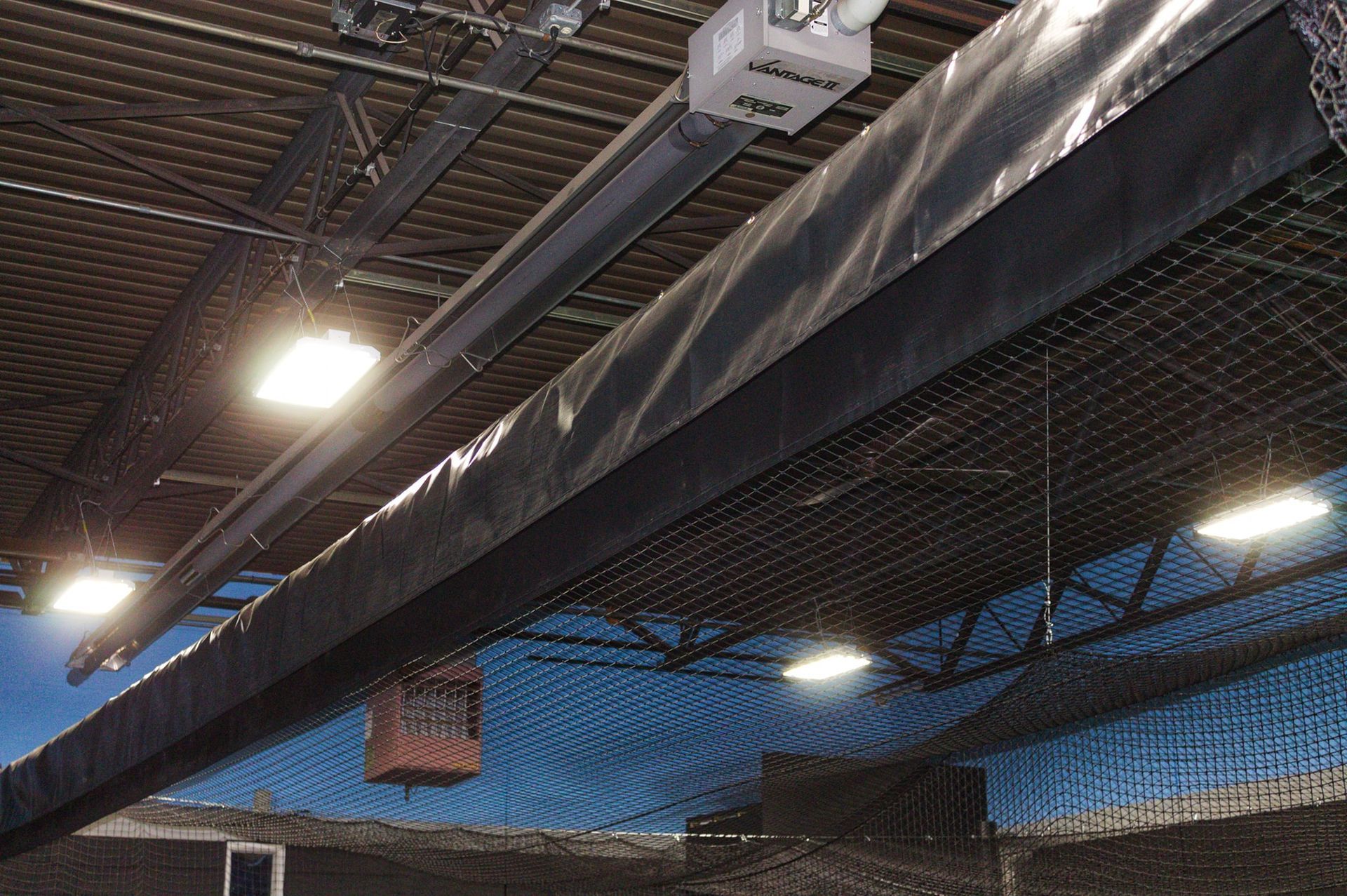 Black netting and equipment hanging from the ceiling of an indoor sports facility.