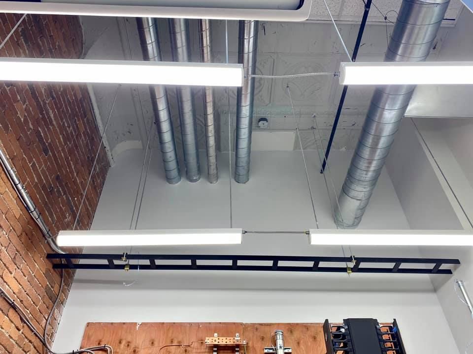 Office ceiling with exposed ductwork, brick wall, and linear lights.