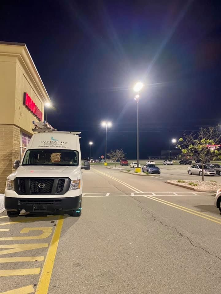 White van parked outside a store at night, under bright streetlights. 