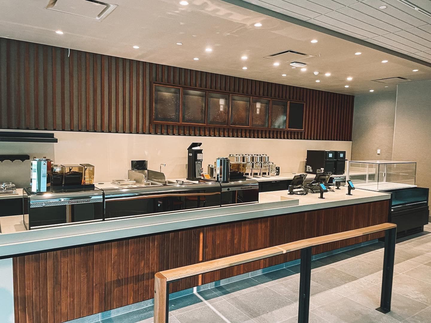 Coffee shop interior with wooden paneling, counter, and equipment.