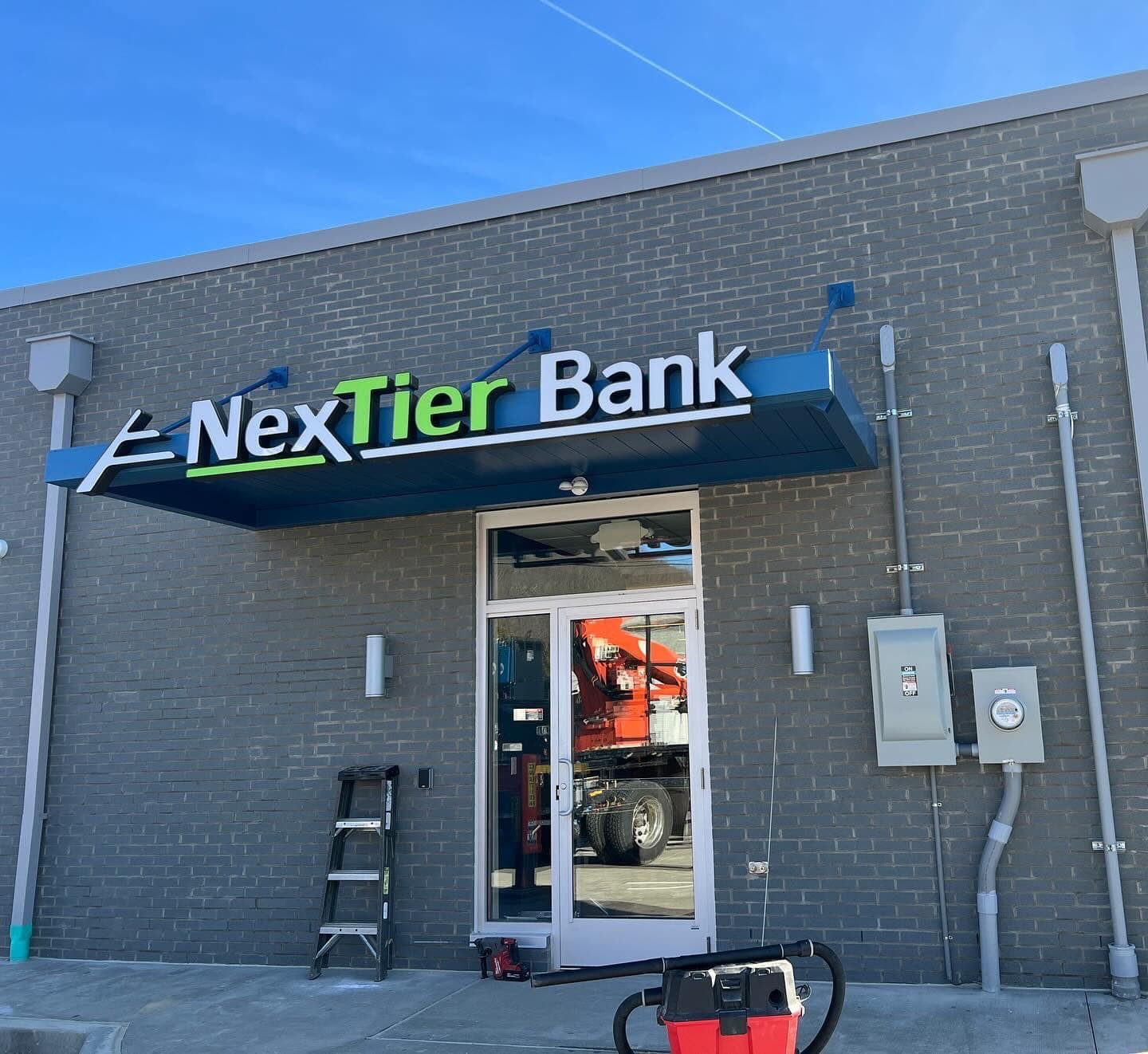 Exterior of NexTier Bank with a blue and green awning above the door.