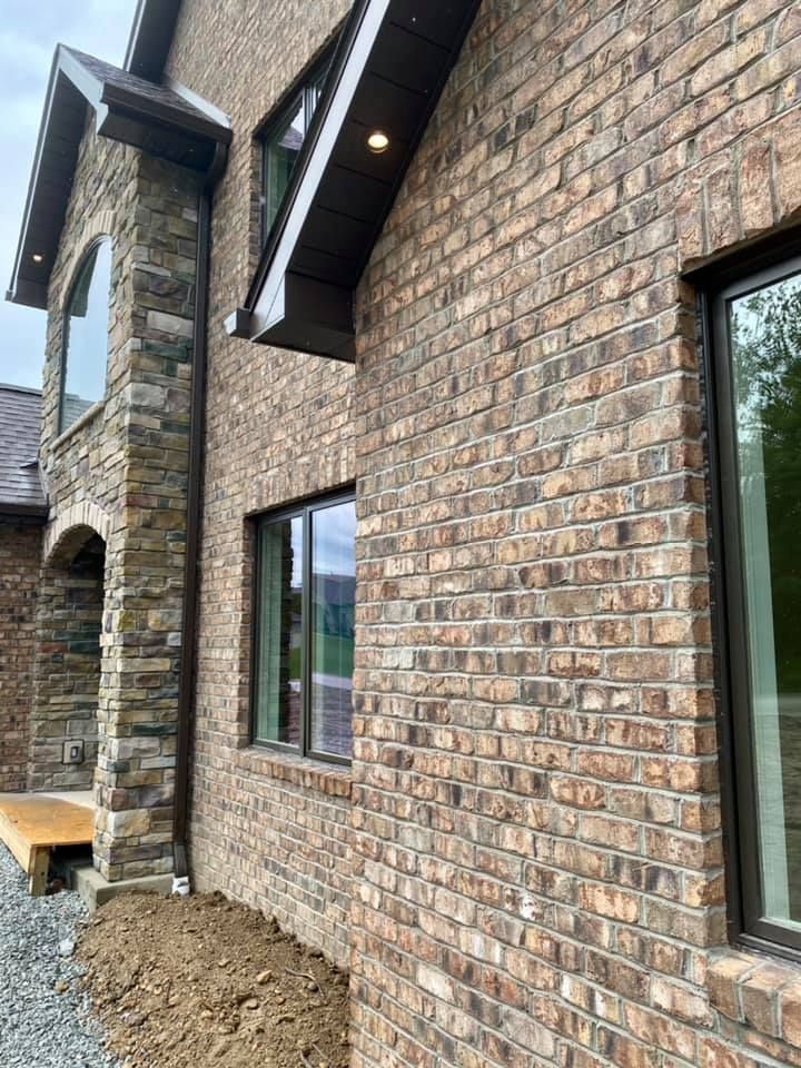 Brick exterior of a house with brown trim and windows. 